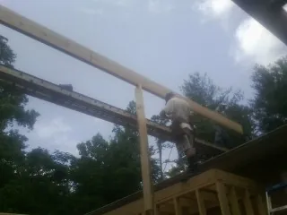 Carpenter setting a ridge beam over a new addition frame — Ice Dam Removal by Roofing Brothers in Bozman