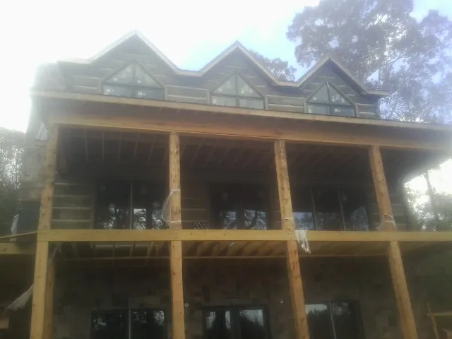 Dormers and porch framing on a large log home under construction — Roof Coating work by our crew in Bozman