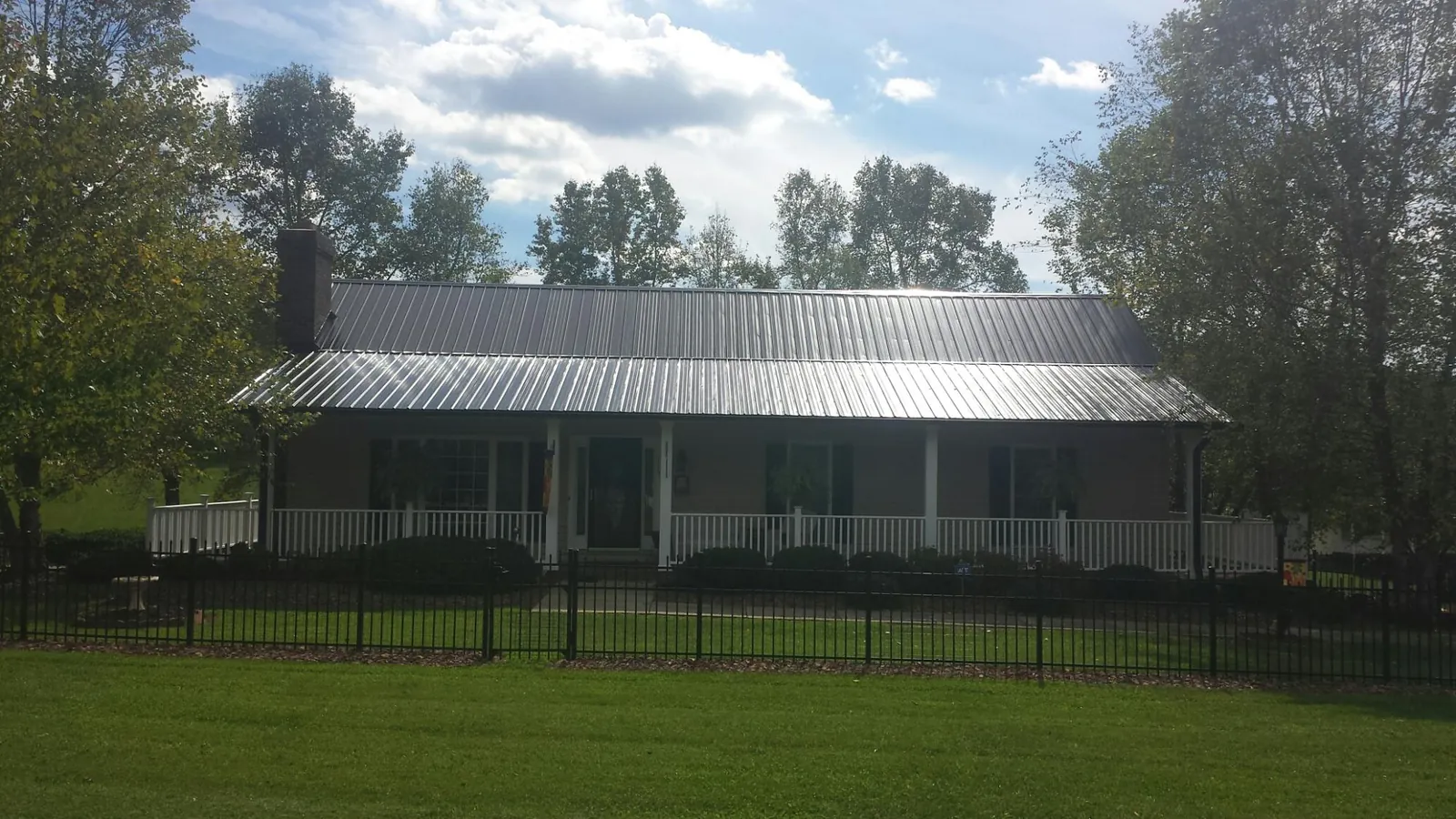 Gray metal roof on a brick ranch with a full width front porch — Gutter Guard Installation work by our crew in Bozman