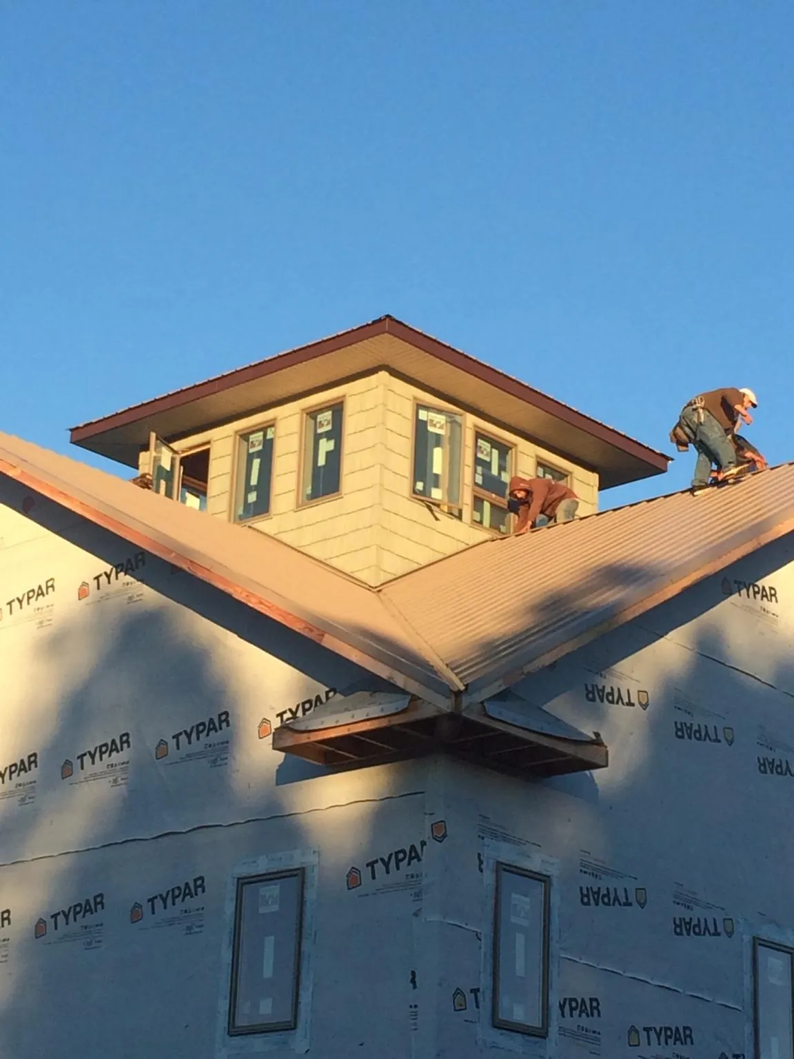 Roofers working around a rooftop cupola on a new metal roof at sunset — Roof Waterproofing in Bozman by Roofing Brothers